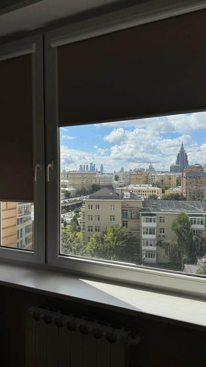 Полотна блэкаут UNI-1 опущены почти полностью — комната в полумраке при ярком дне за окном